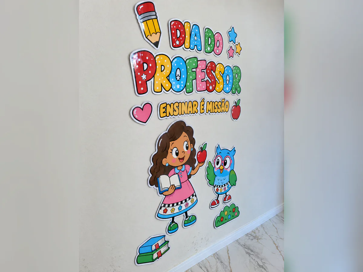 Painel Dia do Professor na parede, visto pela esquerda, com letras coloridas, professora segurando livro e maçã, coruja e elementos escolares.